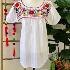 "This traditional Mexican blouse is beautifully made in Merida Yucatan, Mexico, each piece is individually hand made and hand embroidered.  You will love this lightweight blouse made of organic cotton, this natural material gives the blouse a delicate and relaxed feel.   Details: Size M-L measurements: Bust: 42\" - 29\" length(shoulder to bottom Hem) Cotton  thread Embroidered Material: 100% Cotton All items are shipped from the US All Mi Mundo Mexicano  items are 100% handmade by artisans in Mexico. Each stitch and item is completely unique and one-of-a-kind, so you'll never find two that are exactly the same! All  items may vary slightly in size, color, and design - that's what makes handmade items so special and charming!  Your Purchase supports artisans craft and families" Peasant Floral Embroidered Top For Beach, White Top With Chikankari Embroidery For Festivals, White Chikankari Embroidered Top For Festival, Folk Style Peasant Top With Floral Embroidery For Beach, Folk Embroidered Beach Blouse, Folk Style Embroidered Beach Blouse, Embroidered Folk Blouse For Beach, White Floral Embroidered Top For Festivals, White Floral Embroidered Peasant Top