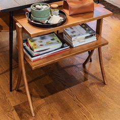 a wooden table topped with books next to a lamp and a bag on top of it