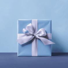 a blue gift box with a white bow on it's side, against a light blue background