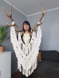 a woman standing in front of a couch holding an animal's skull with large antlers on it