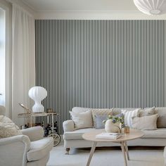 a living room with white furniture and striped wallpaper on the walls, along with a coffee table