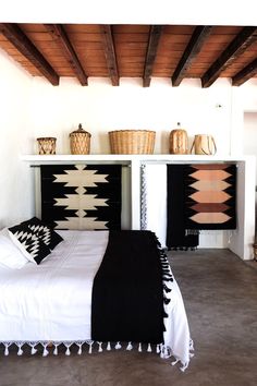 a white bed sitting under a wooden ceiling next to two black and white bedspreads