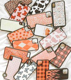 an assortment of cell phone cases sitting on top of a white bed covered in animal print