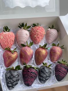 a box filled with chocolate covered strawberries next to pink and white frosted strawberries