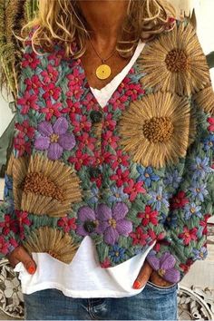 a woman wearing a colorful sweater with sunflowers on the front and back,