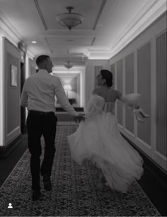 a man and woman walking down a hallway holding hands