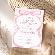 a pink and white birthday party card on top of a table next to a wicker basket