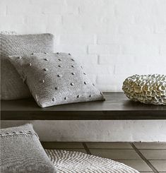 a table with two pillows on it and a vase next to the pillow that has been placed on top