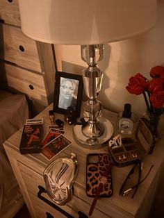 a nightstand with various items on it and a lamp next to it in a bedroom