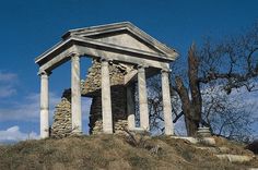 an old stone structure sitting on top of a hill next to a tree with no leaves