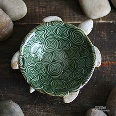 a green bowl sitting on top of a wooden table filled with rocks and pebbles next to it