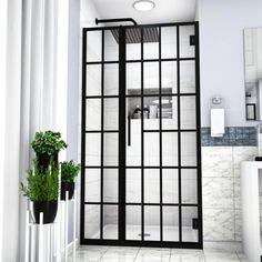 a bathroom with white tile and black glass doors, potted plants in the corner