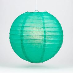 a green paper lantern hanging from a white ceiling with a light on it's side