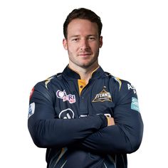 a man with his arms crossed standing in front of a white background wearing a blue jersey