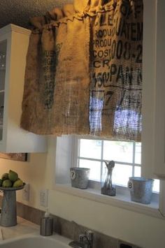 a kitchen with a sink, window and curtain in the corner that has words on it