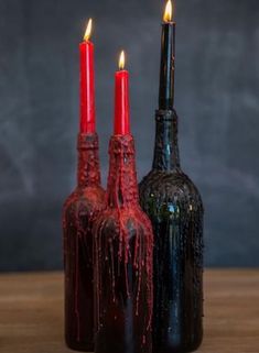 two wine bottles with candles in them sitting on a table