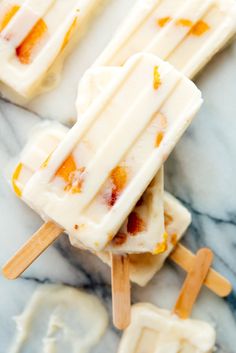 three popsicles sitting on top of a marble counter next to each other with orange and white toppings