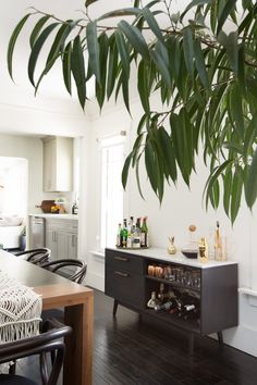 the dining room table is surrounded by black chairs and an open cabinet with wine bottles on it