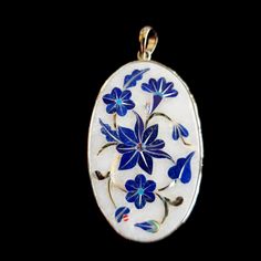 an oval shaped pendant with blue flowers on it