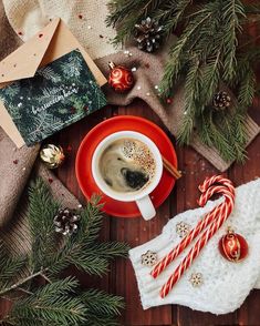 a cup of coffee and candy canes on a wooden table next to christmas decorations