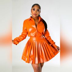 a woman in an orange leather dress posing for the camera with her hands on her hips