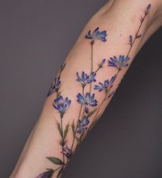 a tattoo with blue flowers on the arm