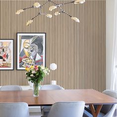 a dining room table with four chairs and two pictures hanging on the wall behind it