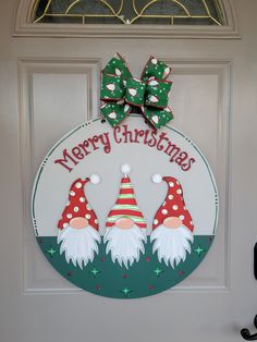 a christmas door hanger with two gnomes on it's face and the words merry christmas