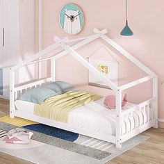 a small white bed with a little house on the headboard and foot board next to it