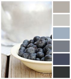 a white bowl filled with blueberries sitting on top of a wooden table next to a color swatch