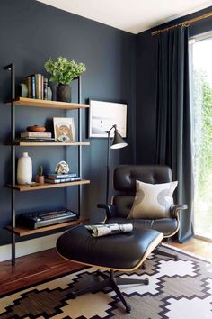 a living room with blue walls and black leather chair in front of a book shelf