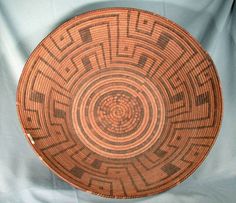 a brown and black basket sitting on top of a blue cloth covered tablecloth with an intricate design in the center