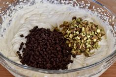 three ingredients in a glass bowl on top of a wooden table, including whipped cream and pistachio