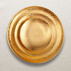 two gold plates sitting side by side on a white surface