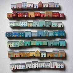 several wooden houses are arranged in a row on a white surface, each painted with different colors