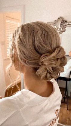 a woman with blonde hair in a messy updo is looking at herself in the mirror