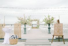 an outdoor ceremony setup with white linens and flowers on the table, along with a sign that says welcome