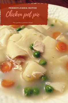 chicken pot pie with carrots and peas on a white plate next to a wooden table