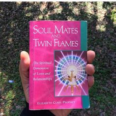 a person holding up a pink book in their hand with the title soul mates and twin flames