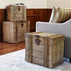 two wooden trunks sitting on top of a white rug next to a chair and ottoman