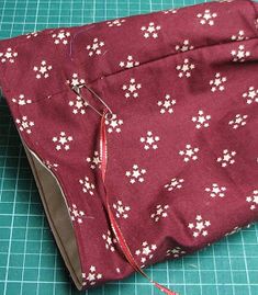 a piece of fabric with white flowers on it sitting on a cutting board next to scissors