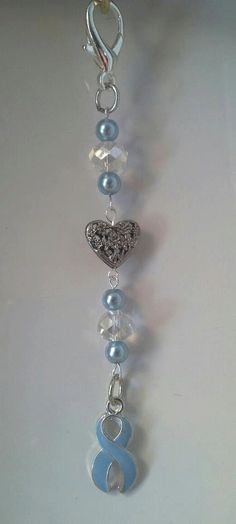 a blue and white beaded necklace hanging from a hook on a chain with charms