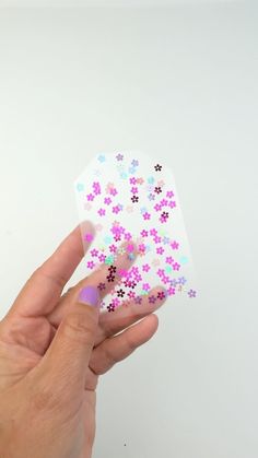 a person's hand holding a small piece of sticker with flowers on it