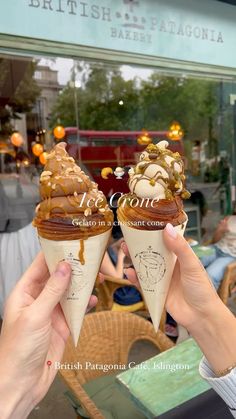 two people holding up ice cream cones with toppings