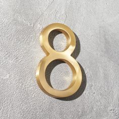 the number 8 is shown in gold on a white wall with grey concrete flooring