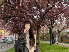 a woman standing in front of a tree with pink flowers