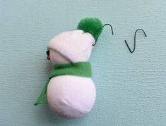 a stuffed snowman hanging on the side of a wall next to a fishing hook