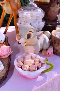 a table topped with lots of candy and stuffed animals on top of wooden stumps