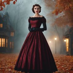 a woman in a long red dress standing on leaves with a house in the background