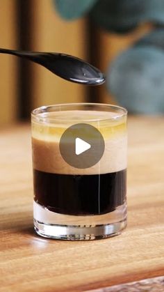 a spoon sticking out of a glass filled with liquid on top of a wooden table